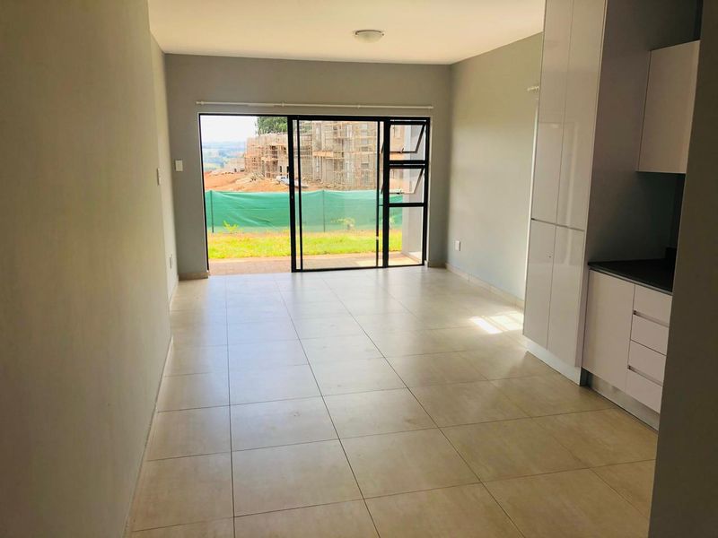 An open-plan living and kitchen area featuring tiled flooring, modern cabinetry, and a large sliding glass door leading to an outdoor space.