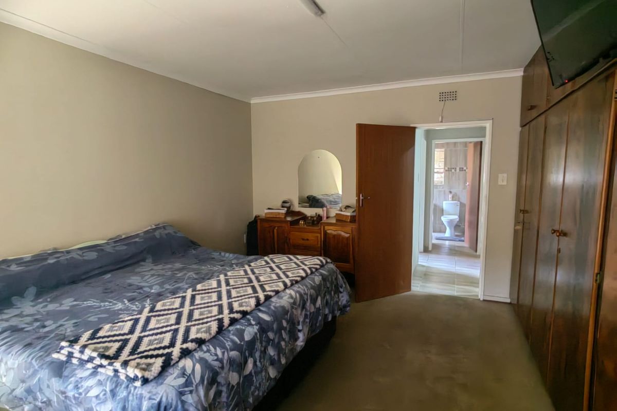 A bedroom featuring built-in wooden cupboards and direct access to an en-suite bathroom.