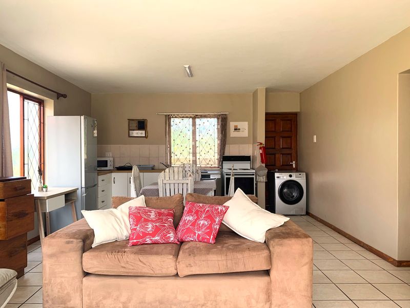 Open-plan living and kitchen area featuring tiled flooring, functional cabinetry, and a freestanding stove, offering a practical layout for daily living.