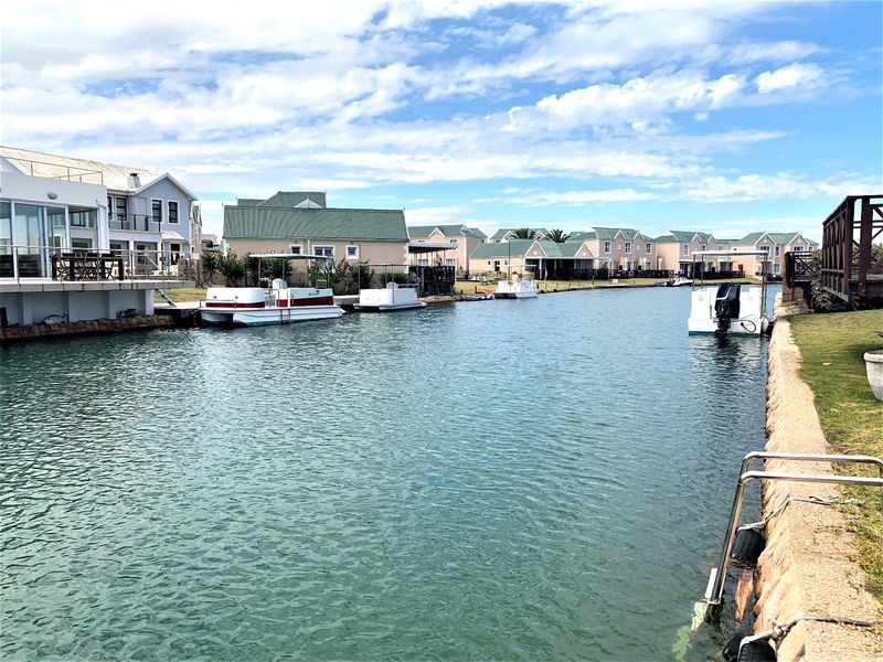 A scenic view of the residential canal system featuring waterfront properties, private jetties, and moored recreational boats.