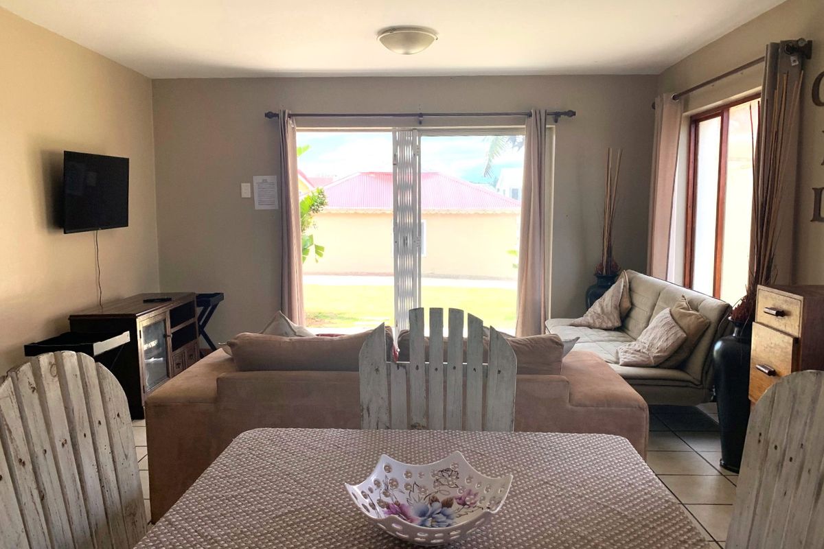 A living room area featuring tiled flooring and a large sliding glass door that provides natural light and access to the exterior.