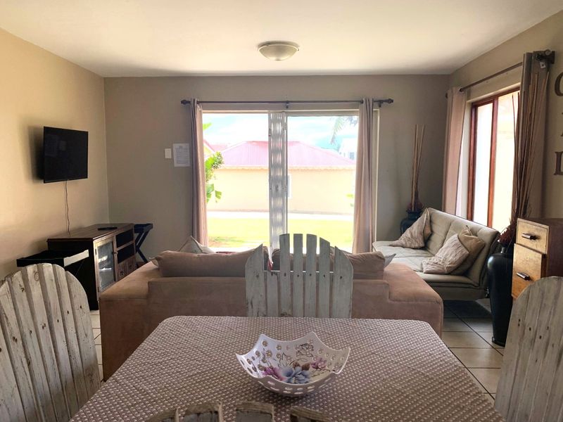 A living room area featuring tiled flooring and a large sliding glass door that provides natural light and access to the exterior.