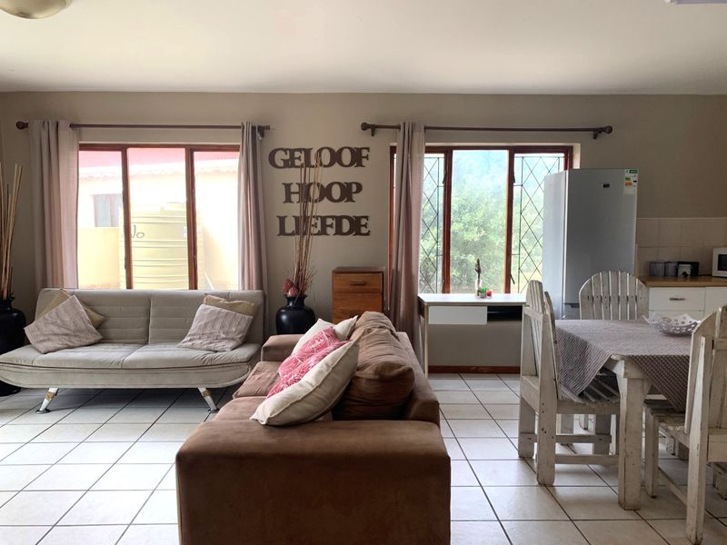 Open-plan living and dining area featuring tiled flooring and large windows, providing a functional space with direct access to the kitchen area.