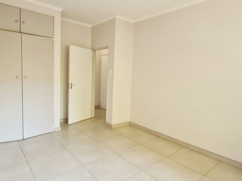 A clean, empty bedroom featuring neutral tiled flooring and built-in storage cupboards, offering a blank canvas for personalization.
