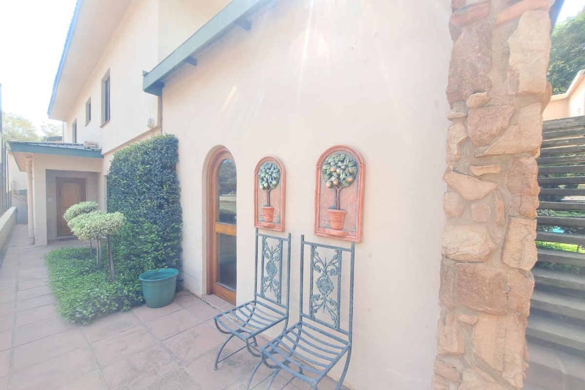 A rear exterior view featuring a tiled patio area, stone-clad pillar, and an arched timber door leading into the home.