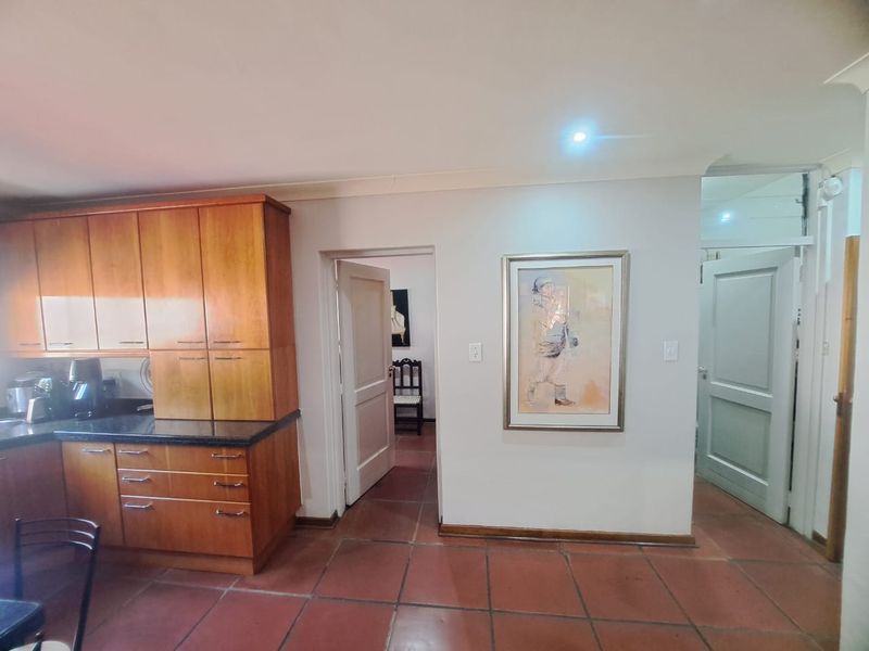 Kitchen area featuring warm-toned wooden cabinetry, granite countertops, and terracotta floor tiles, with direct access to adjacent rooms.
