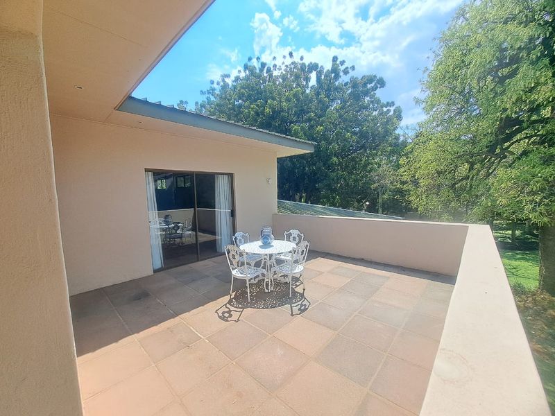 A spacious open-air balcony featuring tiled flooring, recessed lighting, and a solid parapet wall, providing a private outdoor area accessible via sliding glass doors.