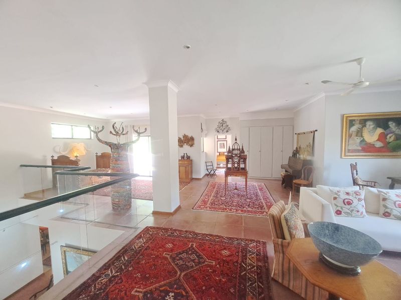 Spacious open-plan living area featuring a glass balustrade, tiled flooring, and built-in storage, offering a bright and versatile layout.