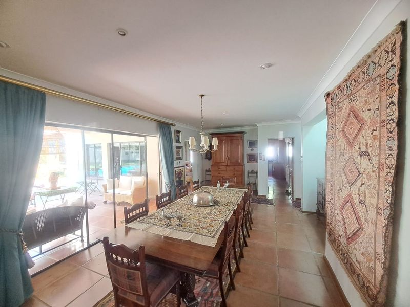 Spacious dining room featuring terracotta floor tiles, recessed lighting, and large sliding glass doors providing direct access to the outdoor patio area.
