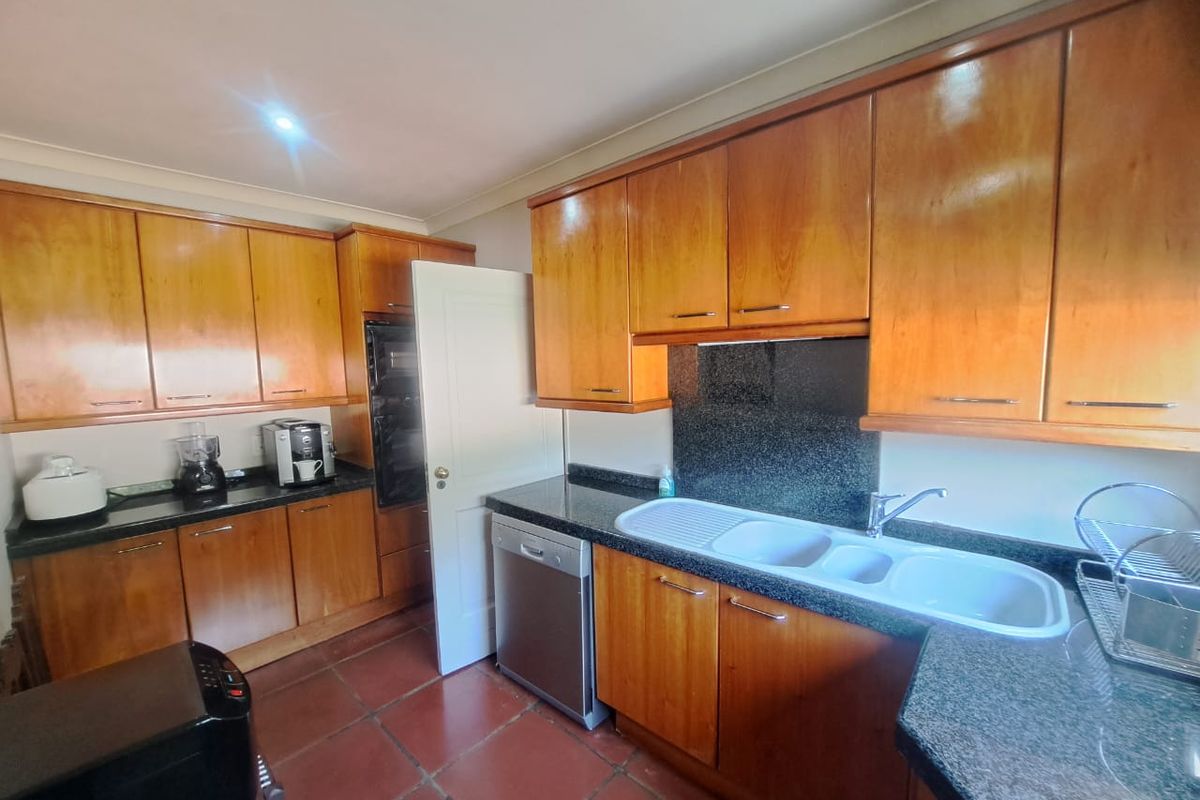 A functional kitchen featuring warm-toned wooden cabinetry, durable granite countertops, a built-in oven, and tiled flooring, offering a classic and practical layout.