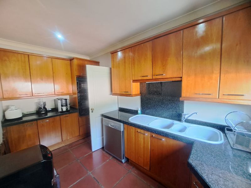 A functional kitchen featuring warm-toned wooden cabinetry, durable granite countertops, a built-in oven, and tiled flooring, offering a classic and practical layout.