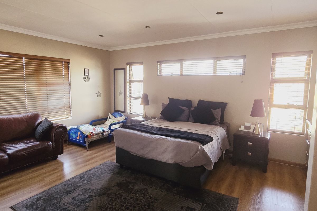 Spacious bedroom featuring laminate flooring, recessed downlighting, and multiple windows fitted with venetian blinds, providing ample natural light.