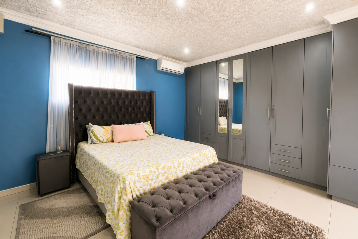 Spacious bedroom featuring extensive built-in grey cabinetry, a split-system air conditioner, tiled flooring, and decorative ceiling finishes.