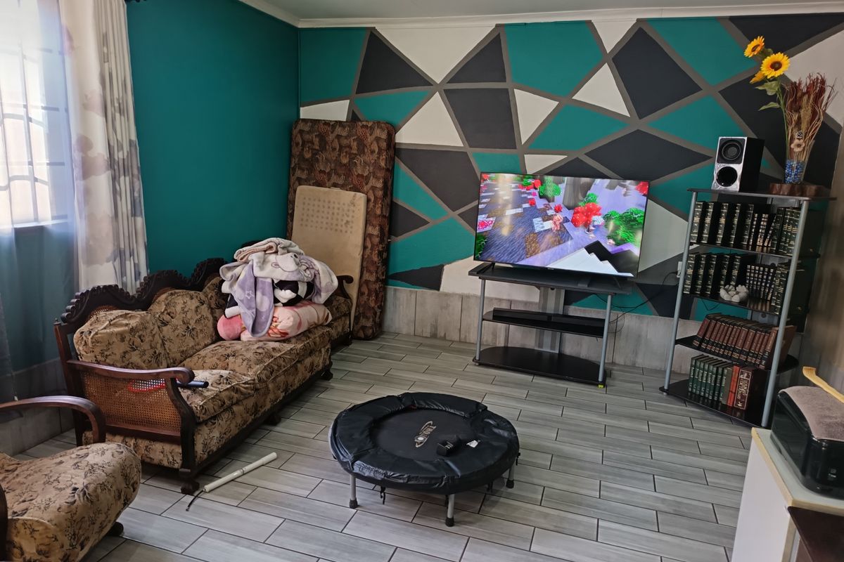 A living room featuring tiled flooring and a bold geometric accent wall, offering a functional space for relaxation.