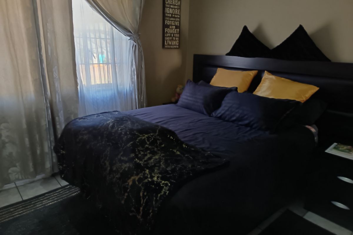 A bedroom featuring tiled flooring and natural light from a window with curtains.