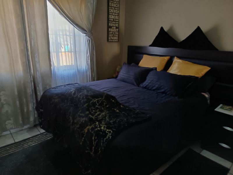 A bedroom featuring tiled flooring and natural light from a window with curtains.