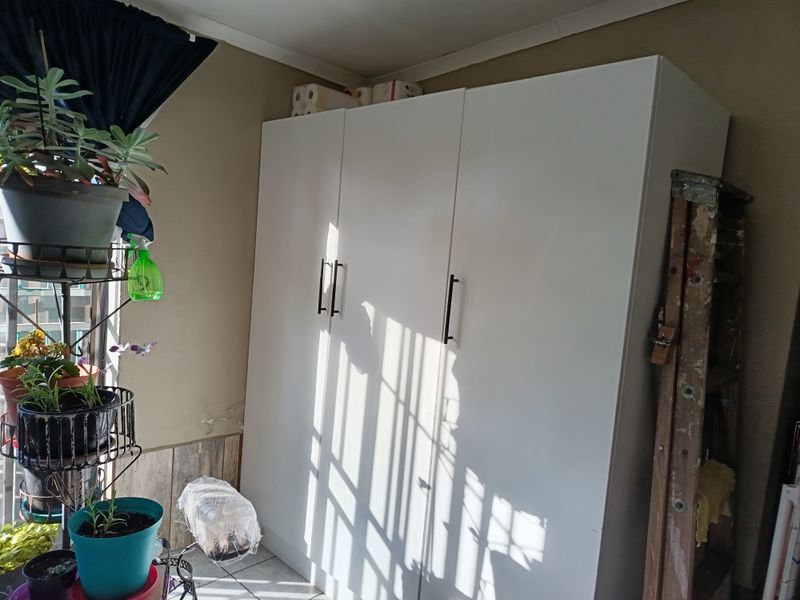 A utility area featuring built-in white cabinetry and tiled flooring, currently showing signs of wall surface deterioration.