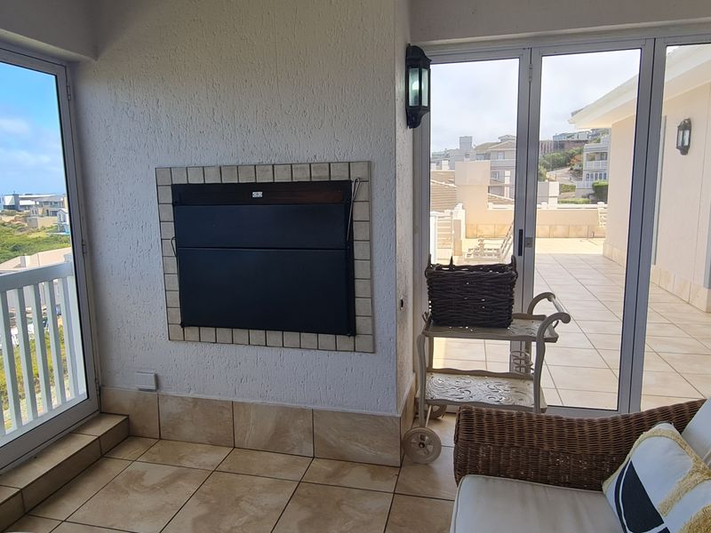 Enclosed balcony featuring tiled flooring, a built-in fireplace, and expansive sliding glass doors offering scenic coastal views.