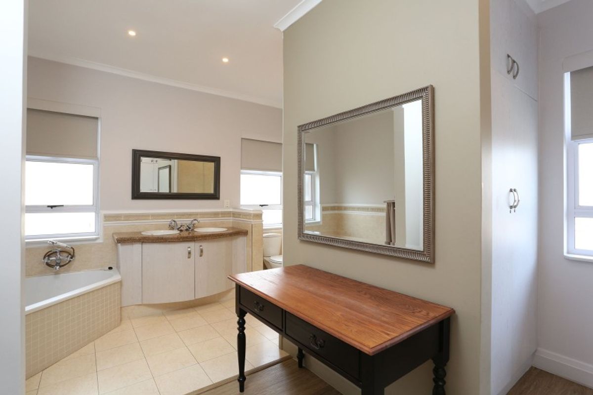 Spacious bathroom featuring a double vanity, built-in bathtub, tiled flooring, and neutral wall finishes with recessed lighting.