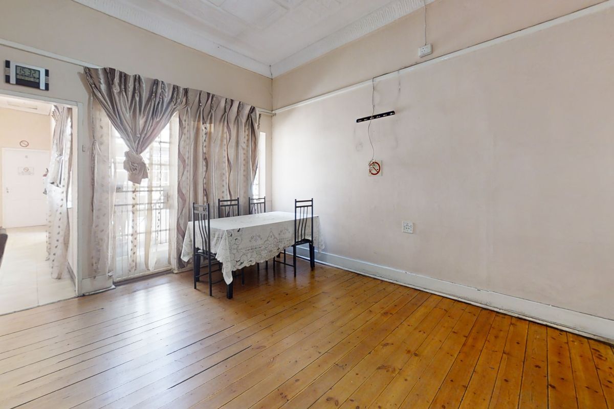 Living area featuring original hardwood flooring, pressed metal ceilings, and classic picture rails, offering a character-filled space in need of cosmetic refurbishment.