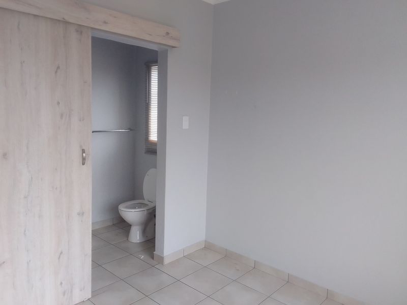 A view of a bathroom featuring a toilet and tiled flooring, accessed via a light wood-finish sliding door.