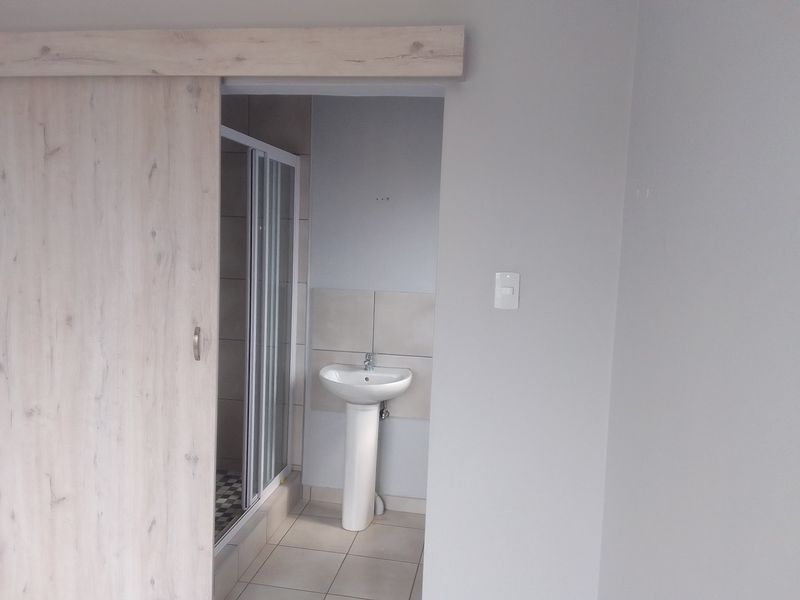A modern bathroom featuring a pedestal basin, a glass-enclosed shower, and a sliding barn-style door entry.
