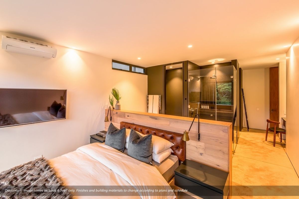Modern bedroom featuring a timber partition wall, integrated glass-enclosed shower, polished concrete floors, and a wall-mounted split-system air conditioner.