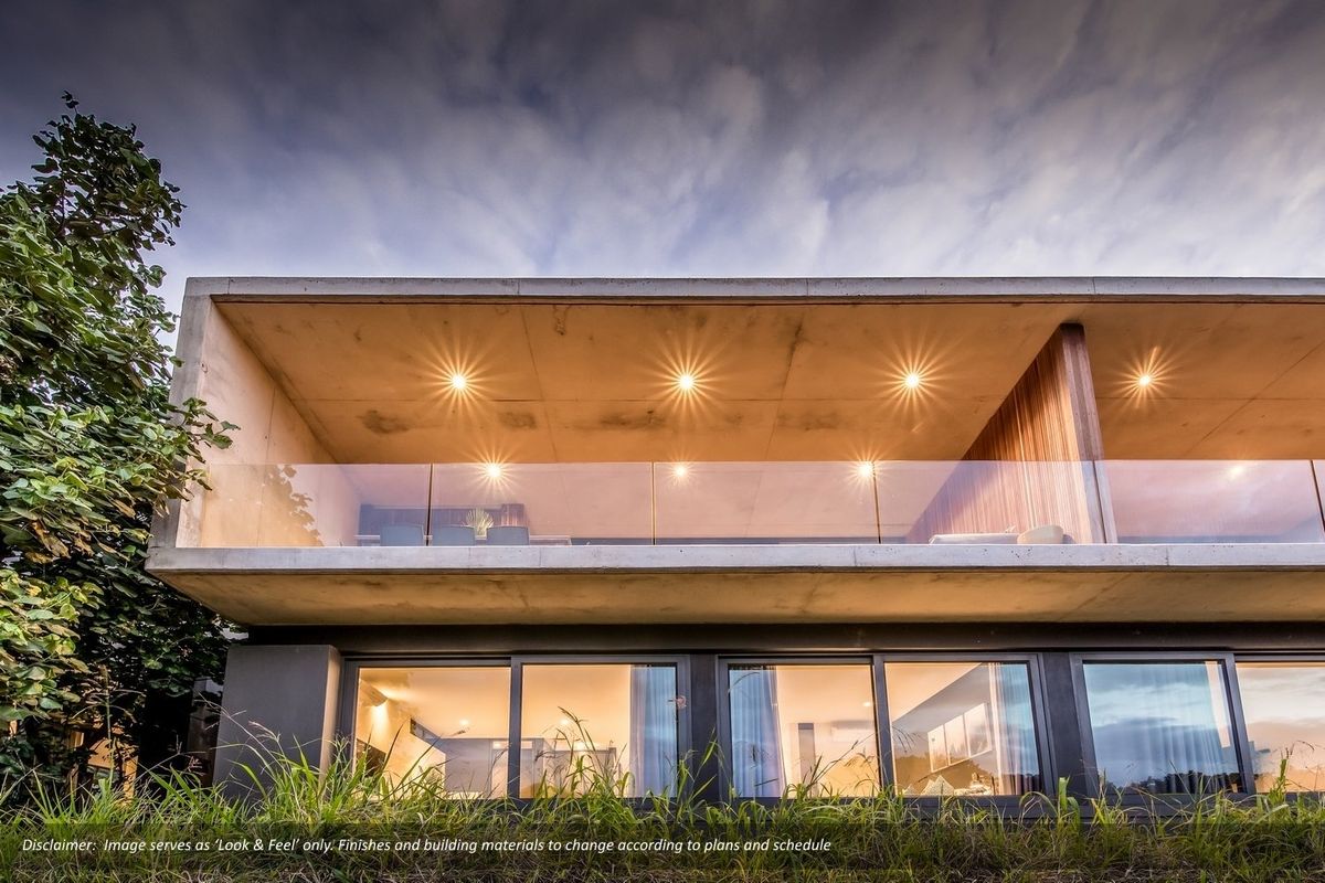 Modern two-story townhouse exterior featuring a concrete balcony with glass balustrades, recessed lighting, and large sliding glass doors.
