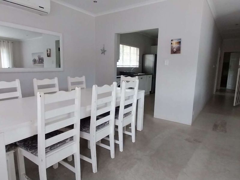 Open plan living and dining area featuring tiled flooring, recessed lighting, and an integrated air conditioning unit, with a view into the adjacent kitchen.