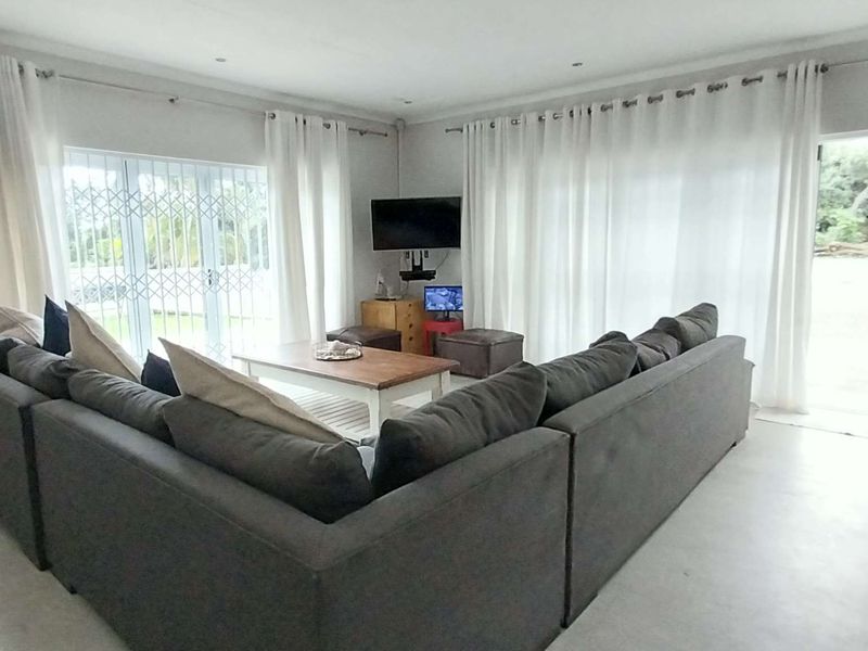 Spacious living room featuring tiled flooring, recessed lighting, and large sliding glass doors with security gates providing access to the outdoor area.