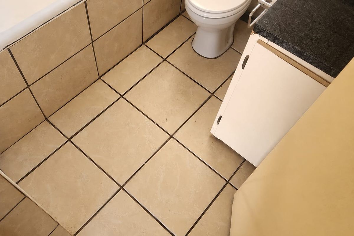 A compact bathroom featuring a bathtub, toilet, and vanity cabinet with a granite countertop, finished with neutral ceramic wall and floor tiles.