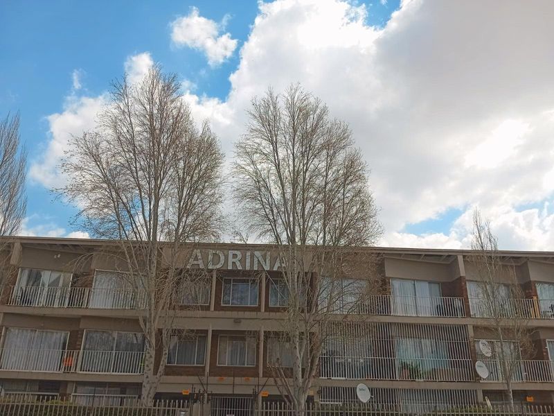 Front elevation of the Adrina apartment complex featuring multi-level balconies with security railings and brick exterior finish.