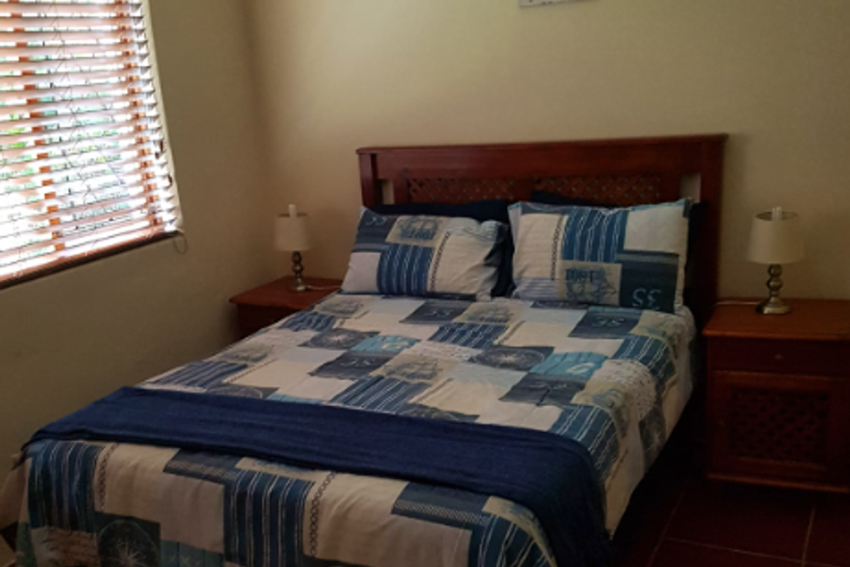 A cozy bedroom featuring tiled flooring and wooden window blinds, providing a comfortable and functional sleeping space.