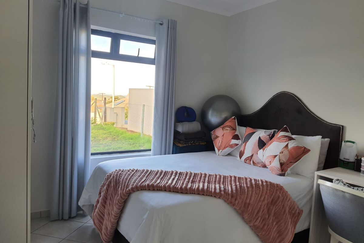 A well-maintained bedroom featuring tiled flooring, a built-in wardrobe, and a large window providing natural light.