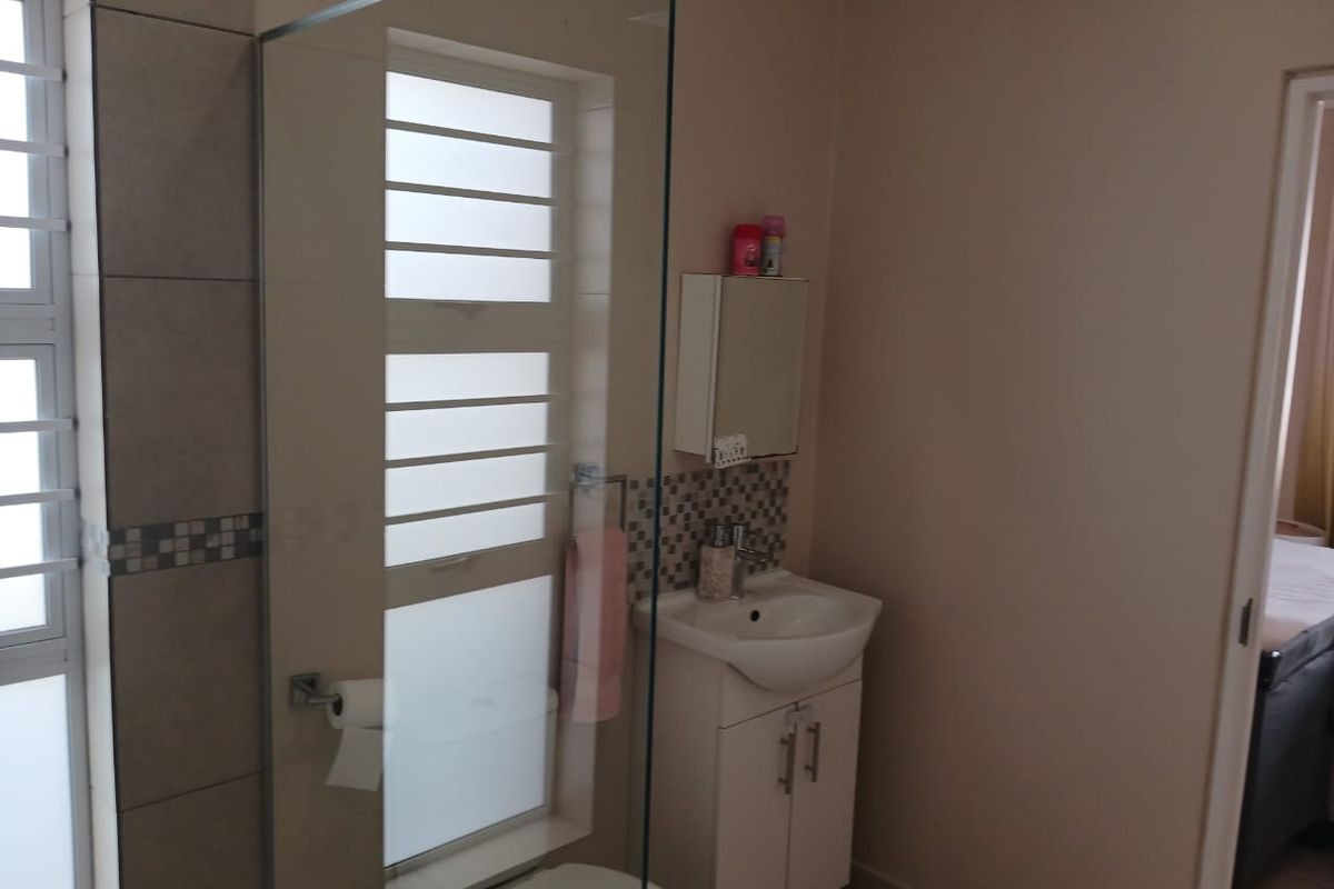 A functional bathroom featuring a glass-enclosed shower, a vanity basin with storage cabinet, and a wall-mounted medicine cabinet.
