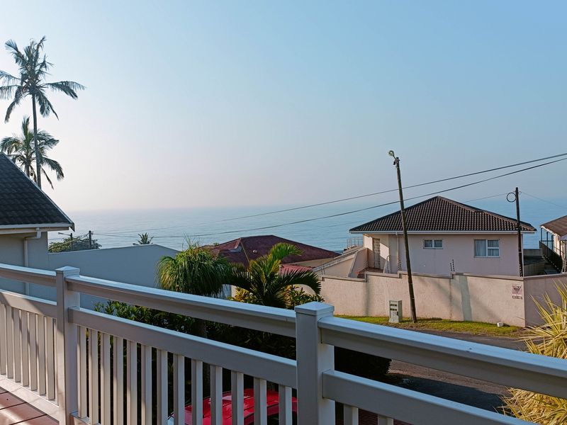 An elevated view from a balcony overlooking the surrounding residential neighbourhood and the ocean horizon.