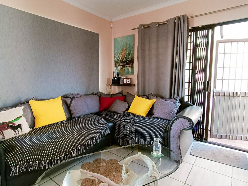 A living room featuring tiled flooring, an accent wall, and a sliding glass door with a security gate leading to the exterior.