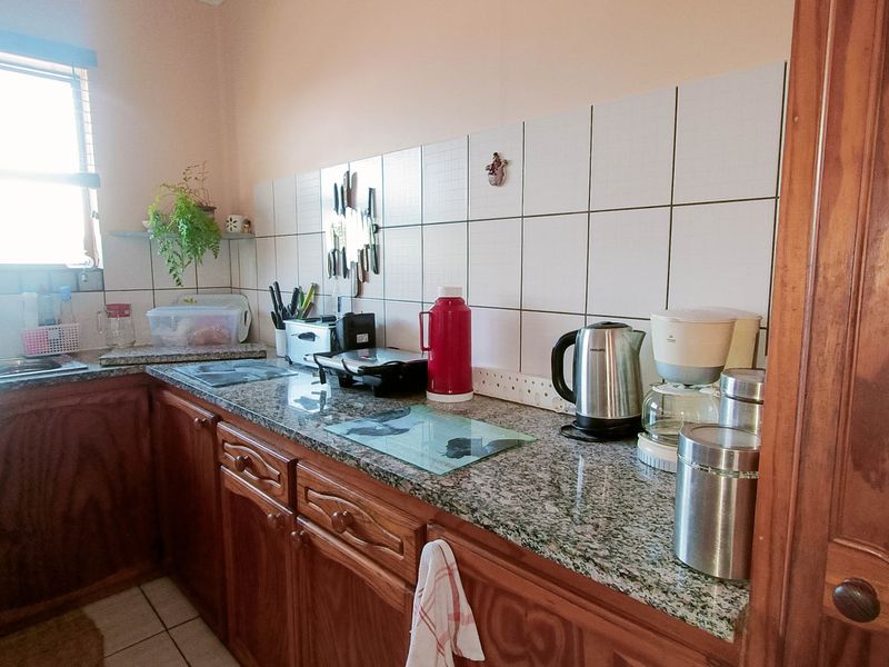 A functional kitchen featuring wooden cabinetry, granite countertops, and a tiled backsplash, providing a practical workspace with a double basin sink.