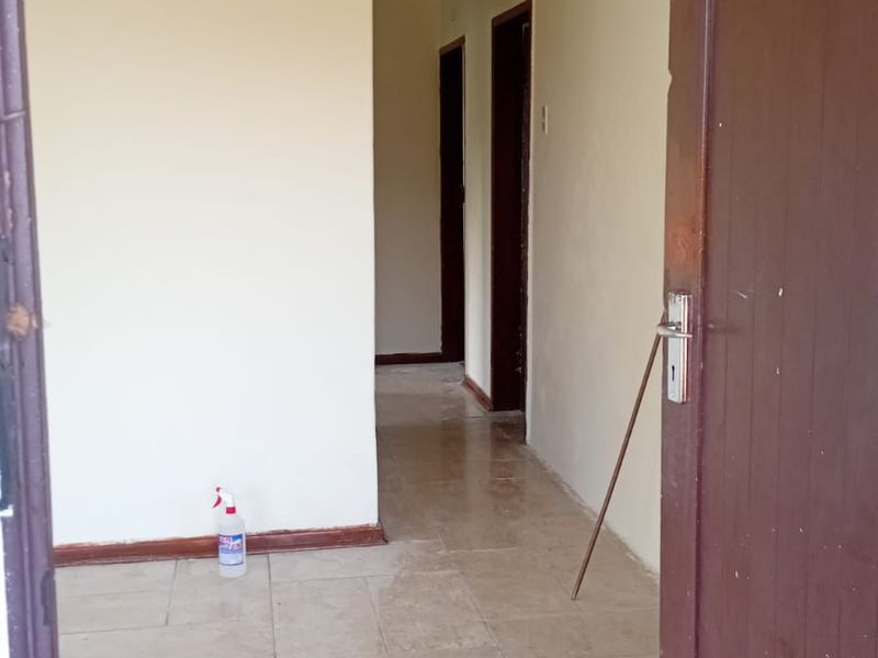 A functional hallway featuring neutral tiled flooring and coved ceilings, providing access to multiple rooms within the property.