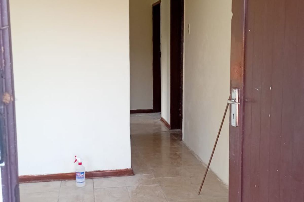 A functional hallway featuring neutral tiled flooring and coved ceilings, providing access to multiple rooms within the property.