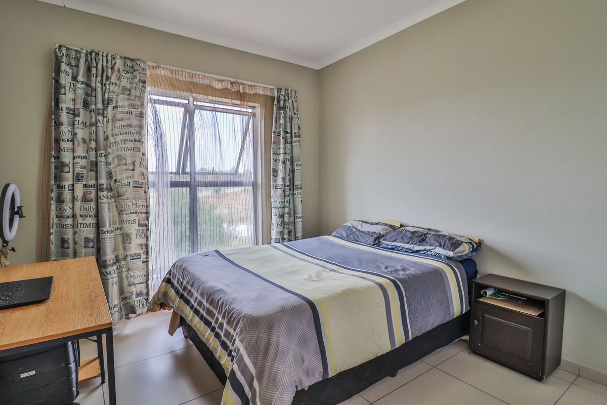 A functional bedroom featuring tiled flooring, a top-hung window, and neutral wall finishes, providing a comfortable and well-lit living space.