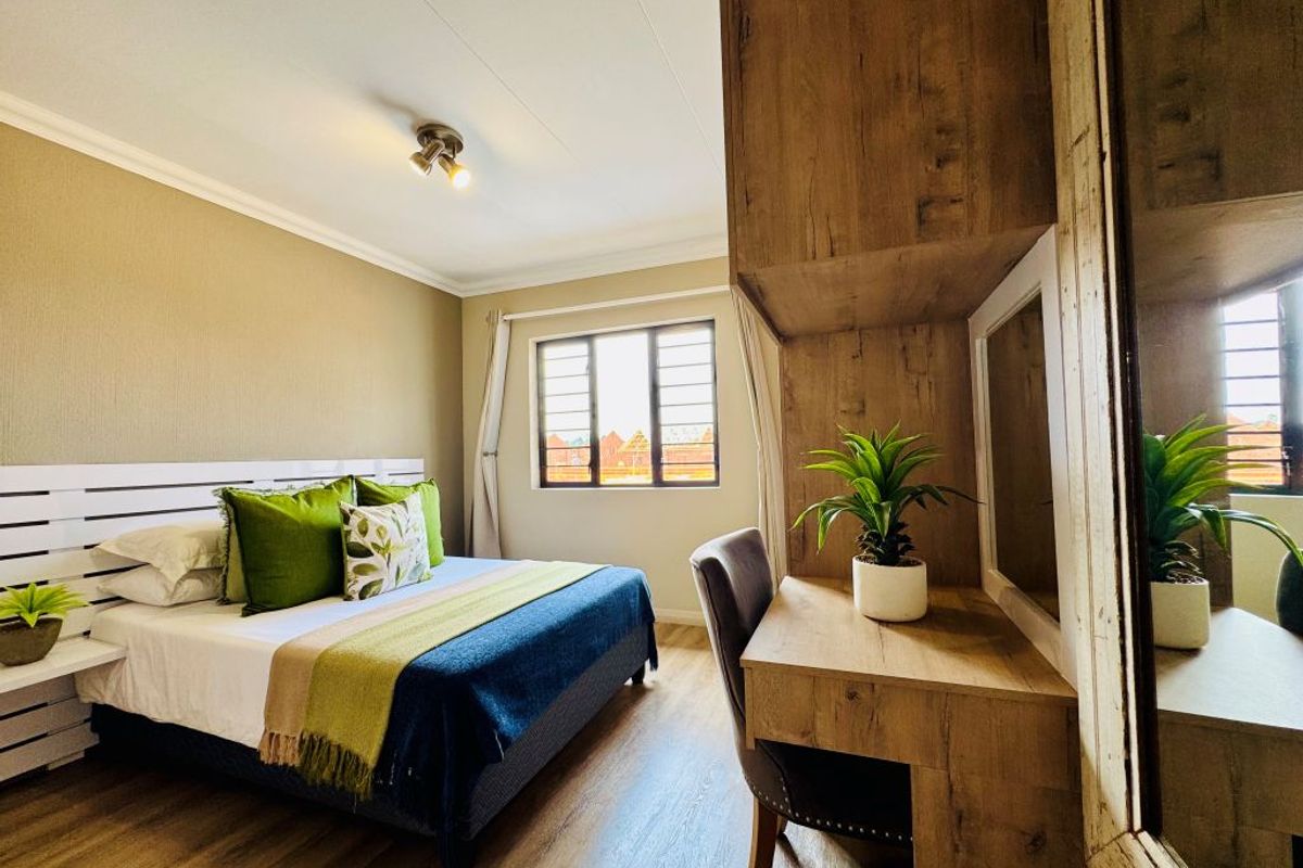 A well-maintained bedroom featuring laminate flooring, a built-in vanity unit, and a window with security bars, offering a functional and comfortable living space.