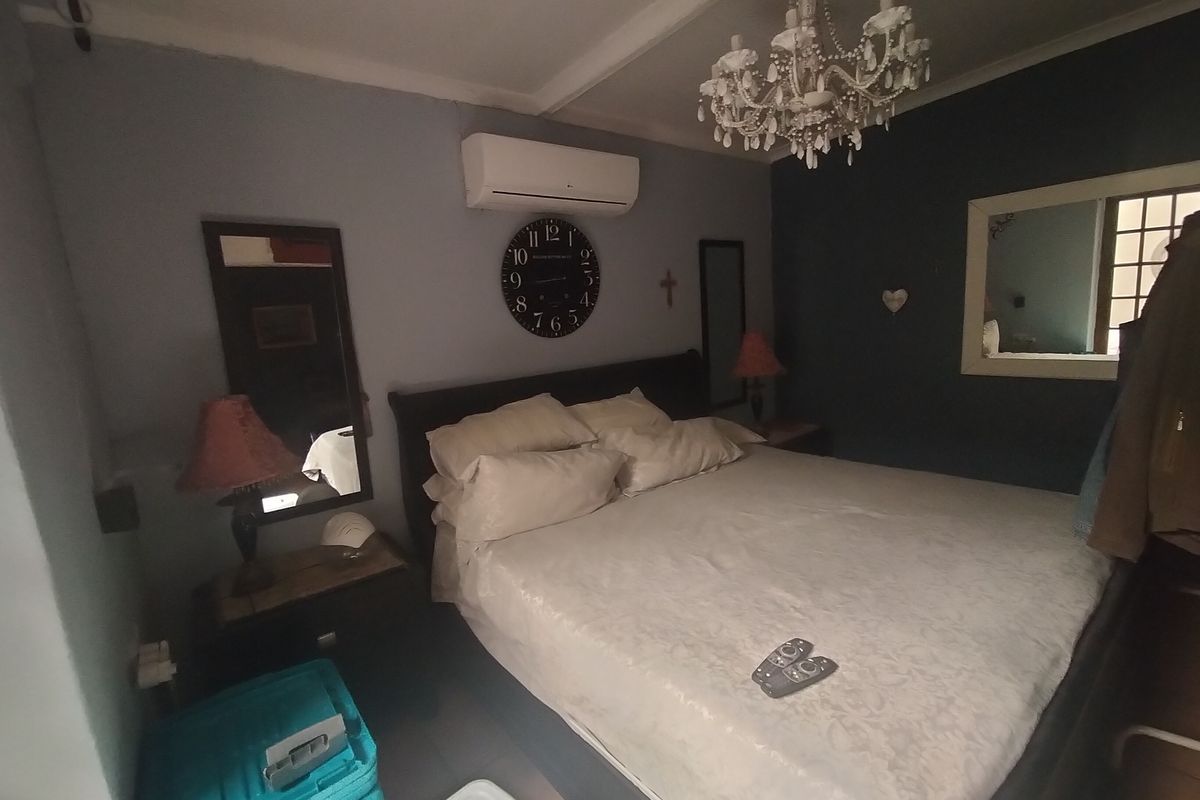 A bedroom featuring a split-system air conditioner and a decorative chandelier, providing a functional space with neutral wall tones.