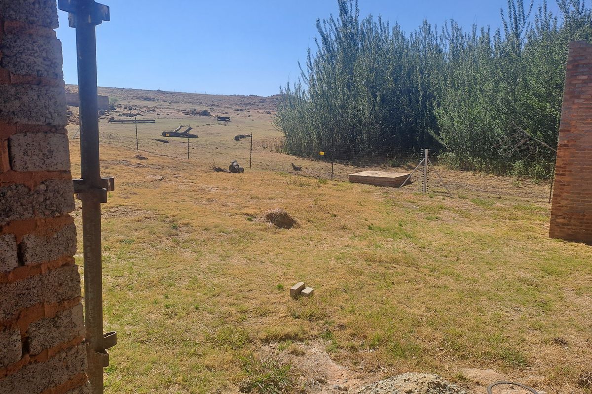 View of the rear farm grounds featuring wire fencing, established trees, and open land, showing potential for further development or landscaping.