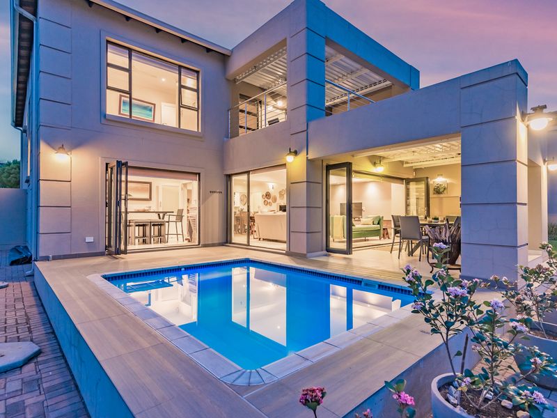 Modern double-story residence featuring a swimming pool, tiled deck, and seamless indoor-outdoor flow through large bi-fold doors to a covered patio area.