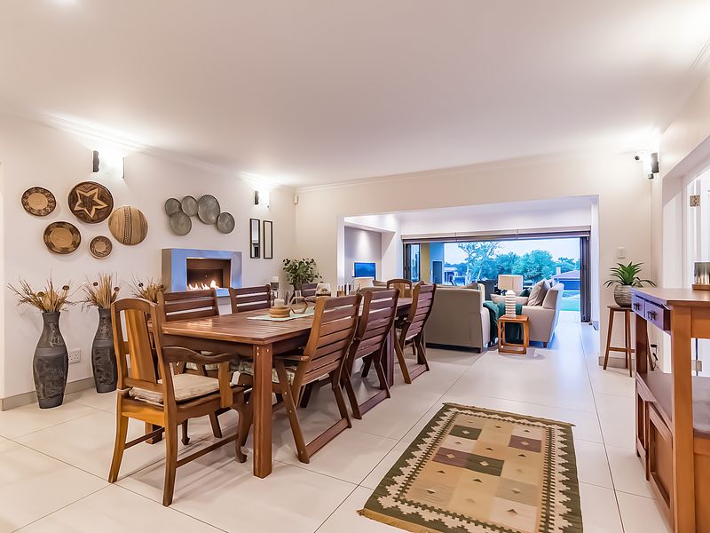 Spacious open-plan dining and living area featuring a modern built-in fireplace, tiled flooring, and large sliding doors opening to the outdoor space.