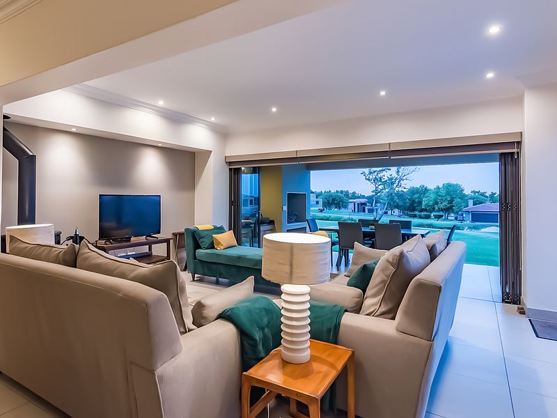 Spacious open-plan living area featuring modern recessed lighting, a fireplace, and large stacking doors that seamlessly connect to the outdoor patio and garden.