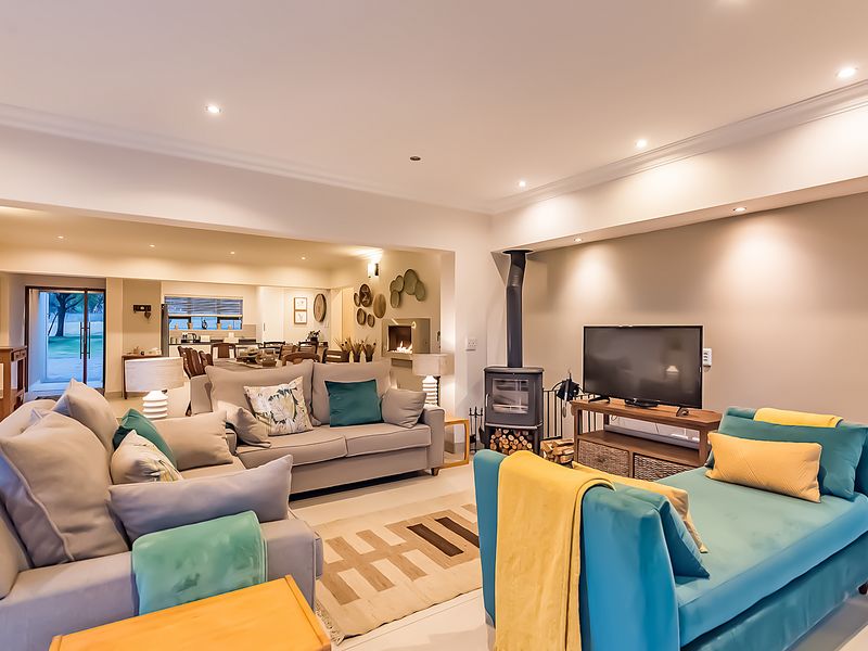 Spacious open-plan living area featuring a modern freestanding fireplace, recessed lighting, and seamless flow to the kitchen and dining space.