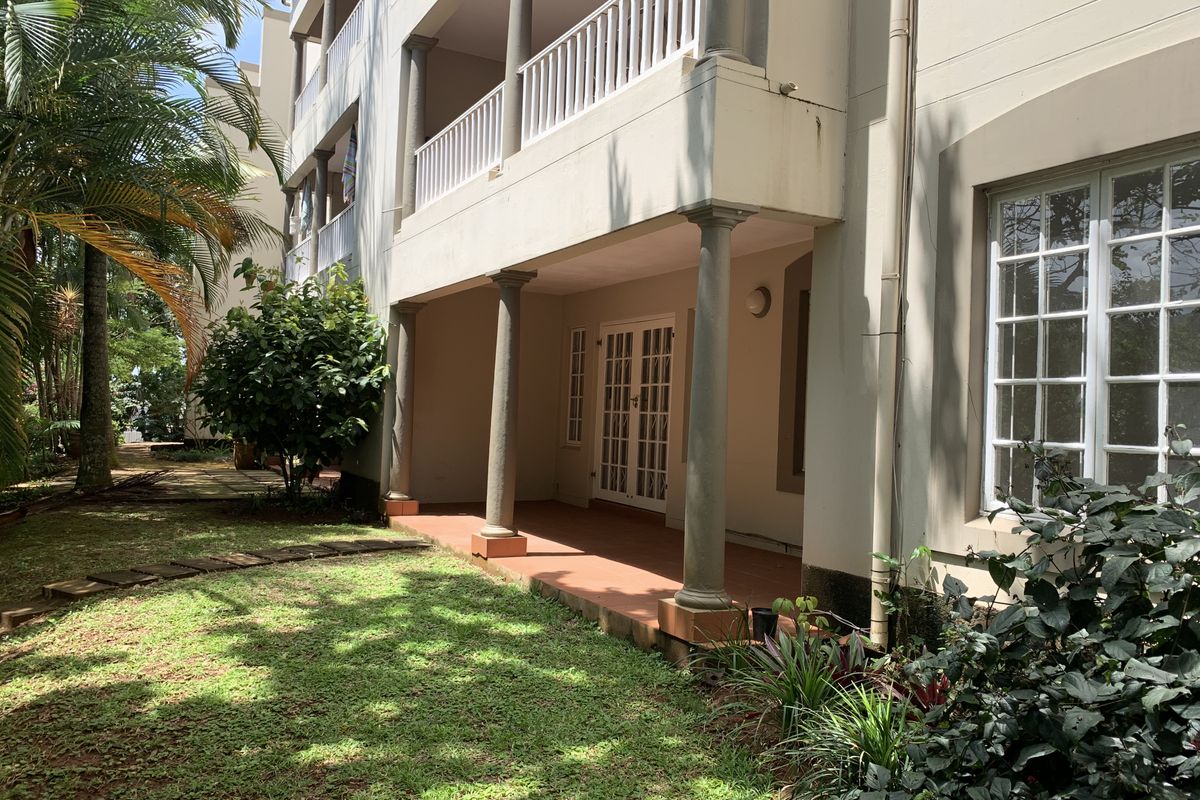 A ground floor covered patio area with access via French doors, featuring structural columns and overlooking a private garden space.