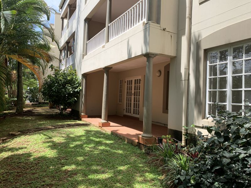 A ground floor covered patio area with access via French doors, featuring structural columns and overlooking a private garden space.